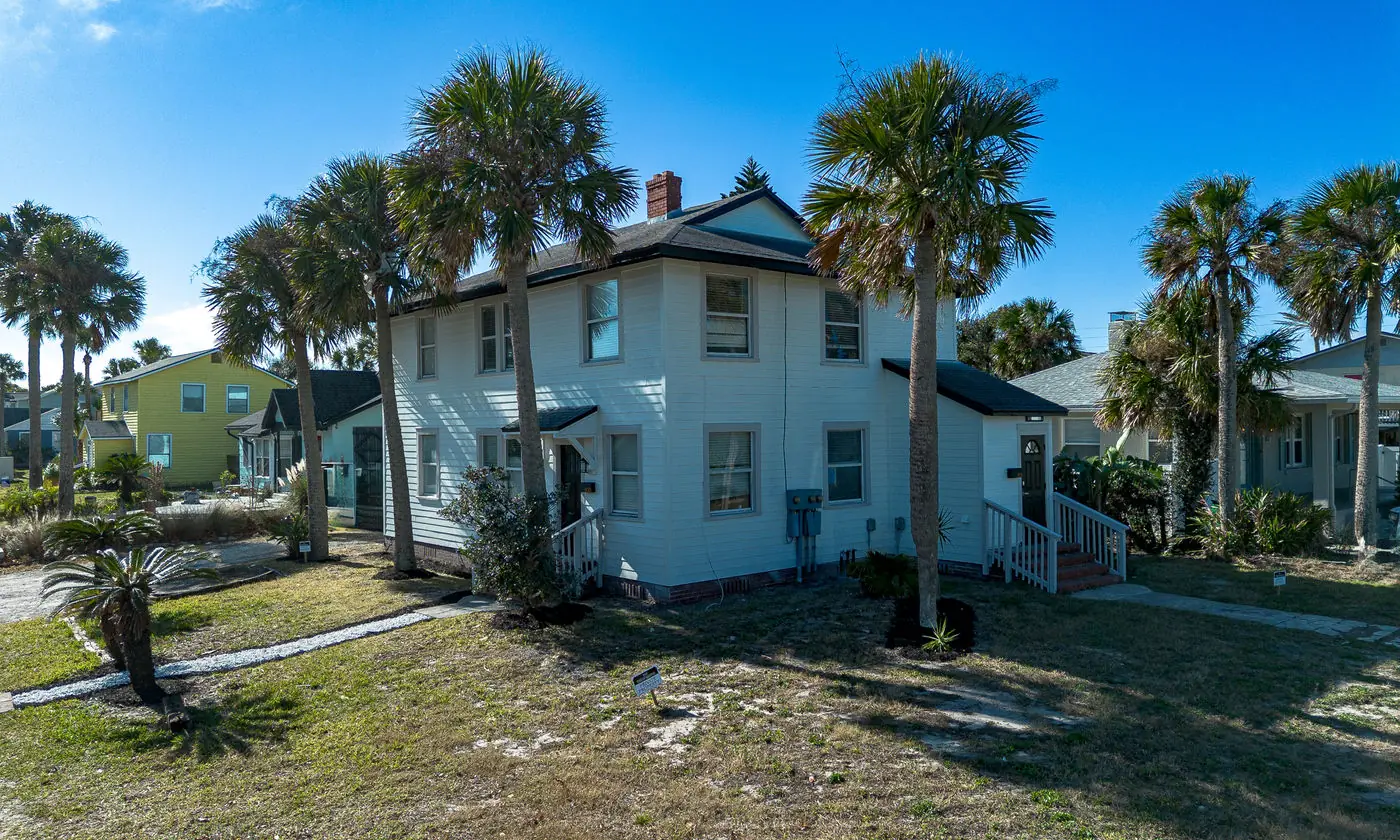 White two-story building among palms at Neptune Beach